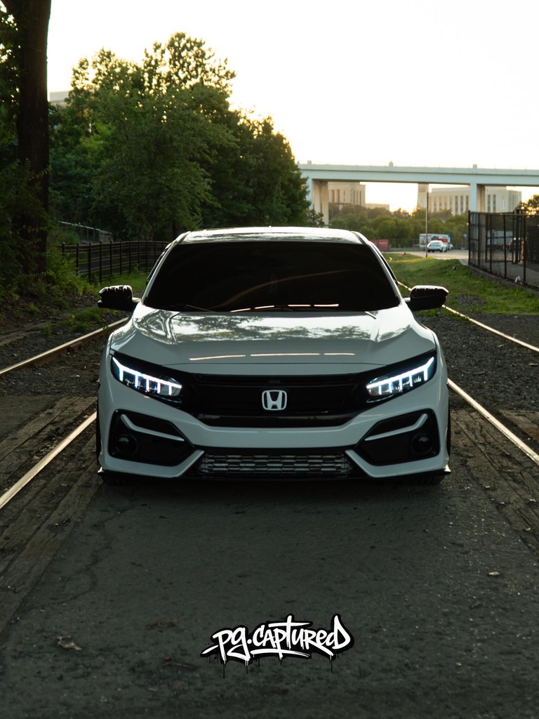 White Honda photographed by railroad tracks