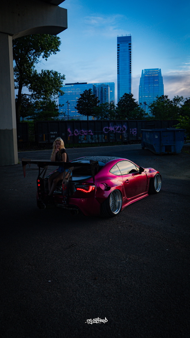 Pink widebody sports car with the Nashville skyline